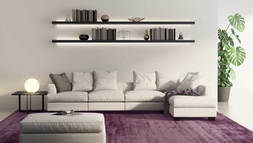 A white sofa, purple carpet, and black wall shelves featuring reccessed lights in a living room
