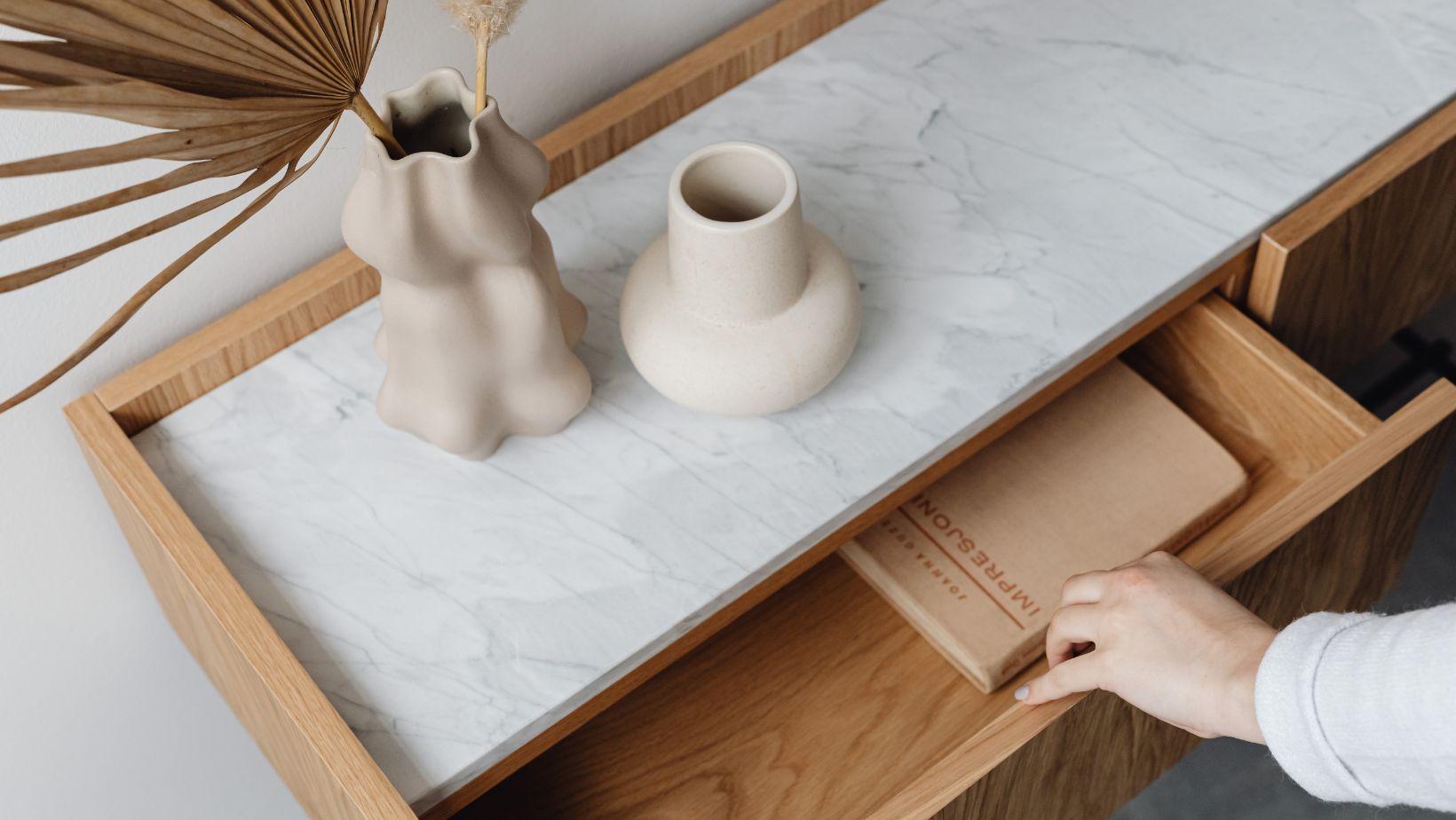 A hand opening a wooden drawer